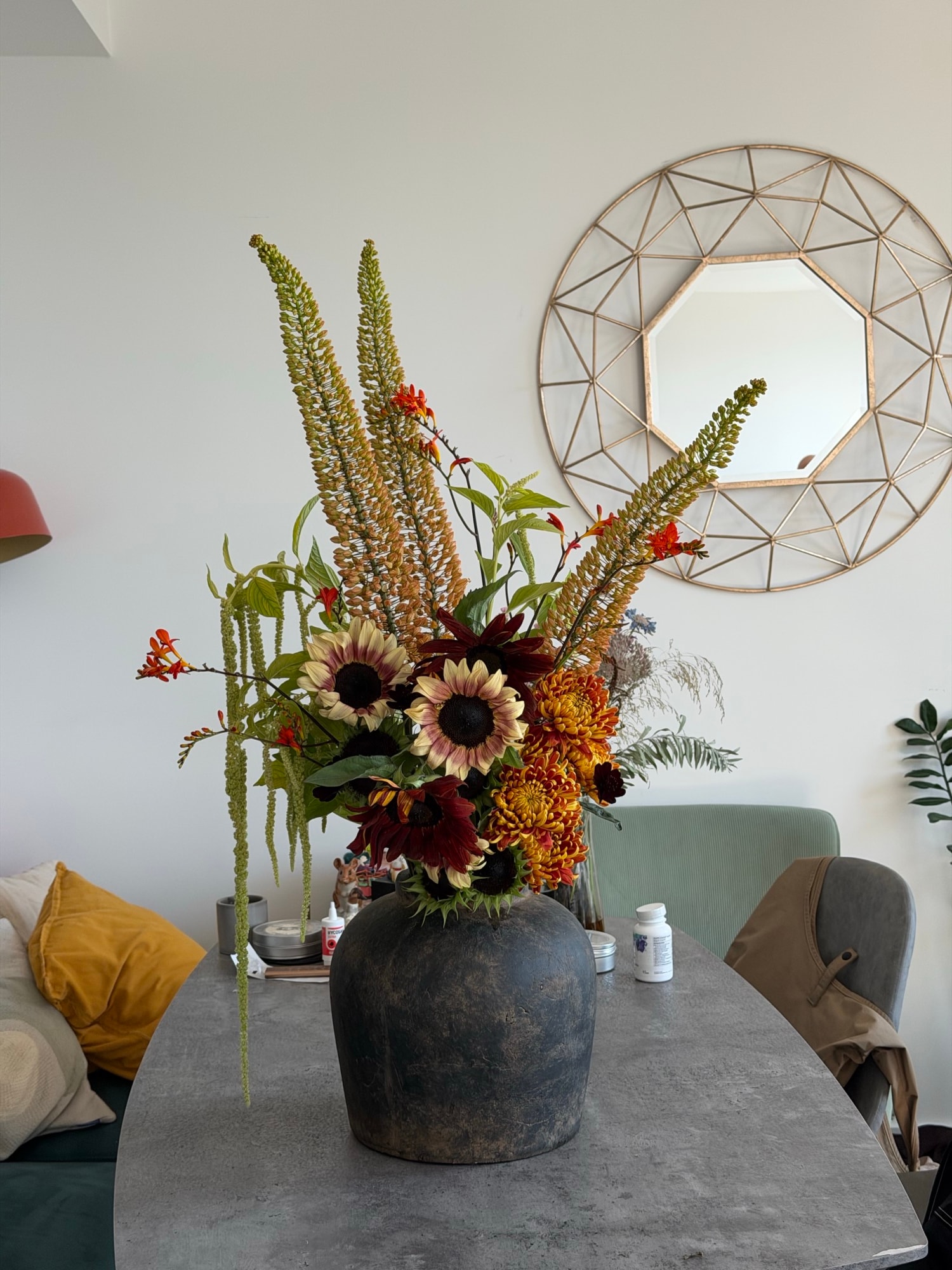 Wild autumnal arrangement of sunflowers, foxtail lilies, and burgundy blooms in a dark textured vase