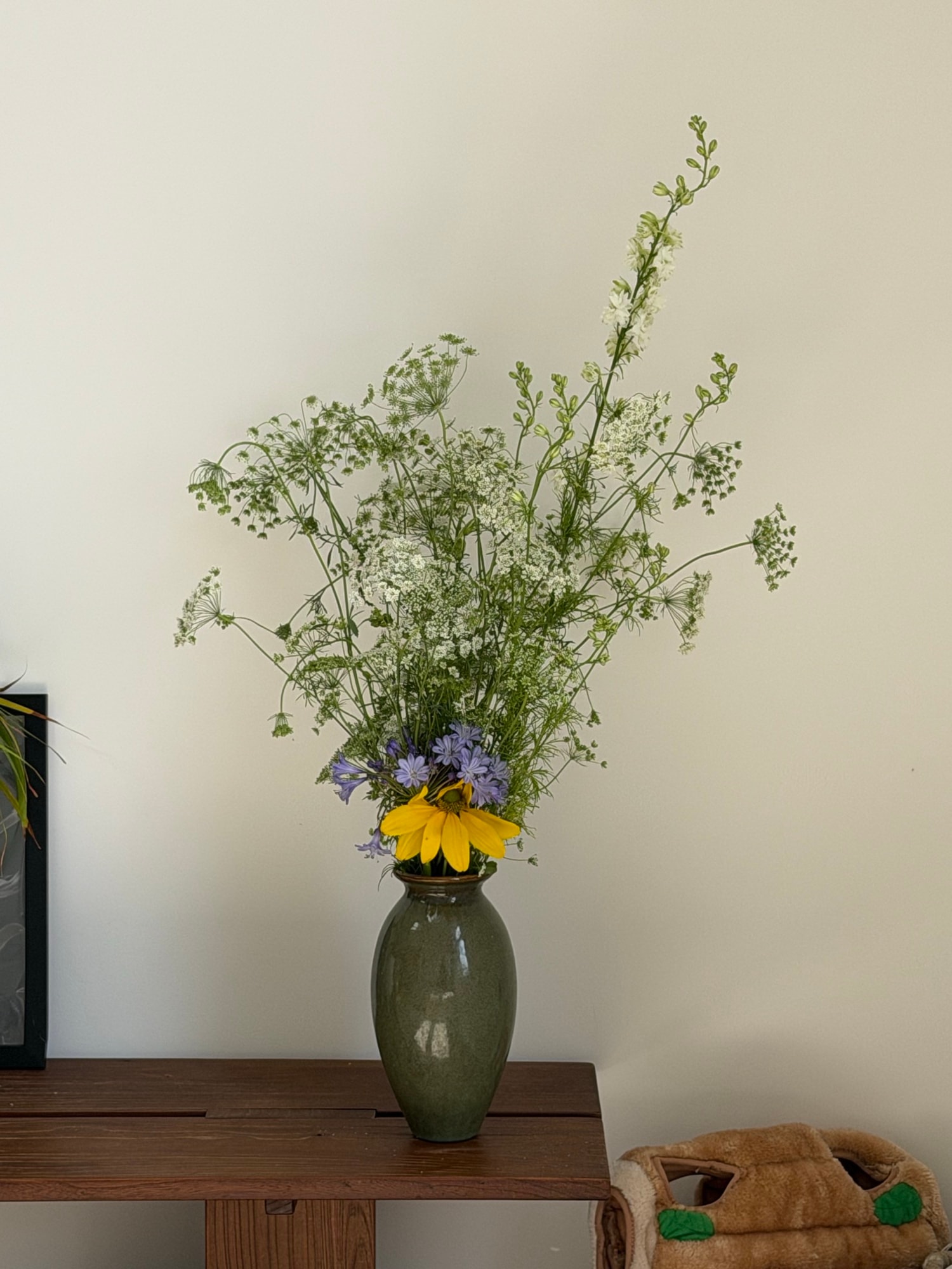 Airy Queen Anne's lace arrangement in green vase against white wall