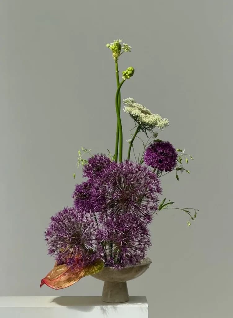 Purple alliums and anthurium on a stone pedestal